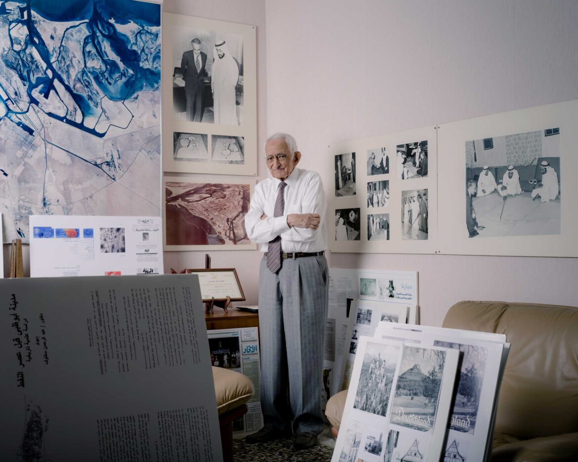 Surrounded by memories of past achievements, Dr. Makhlouf stands in his conference room in Abu Dhabi, on November 6, 2012. The exhibition boards illustrate
his early education in Quranic and Arabic studies in Cairo, doctorate studies in Germany, and the presentation of his master plans on the palace floors of Abu Dhabi. On the upper left appears a satellite image of the emirate that has been his home since 1968. Photograph by Ziyah Gafic.