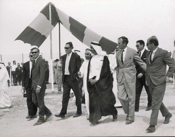 Photograph of the ruler of Dubai, Sheikh Rashid bin Saeed Al Maktoum, and (left) adviser Mahdi Al Tajir flanked by British architect Keith Page (left) and Julian Bullard, the penultimate British political agent before federation. This might be at a groundbreaking ceremony in 1969. Some of the other men in photograph possibly represent Costain. Courtesy of Catherine, Fiona, and Jackie Page.